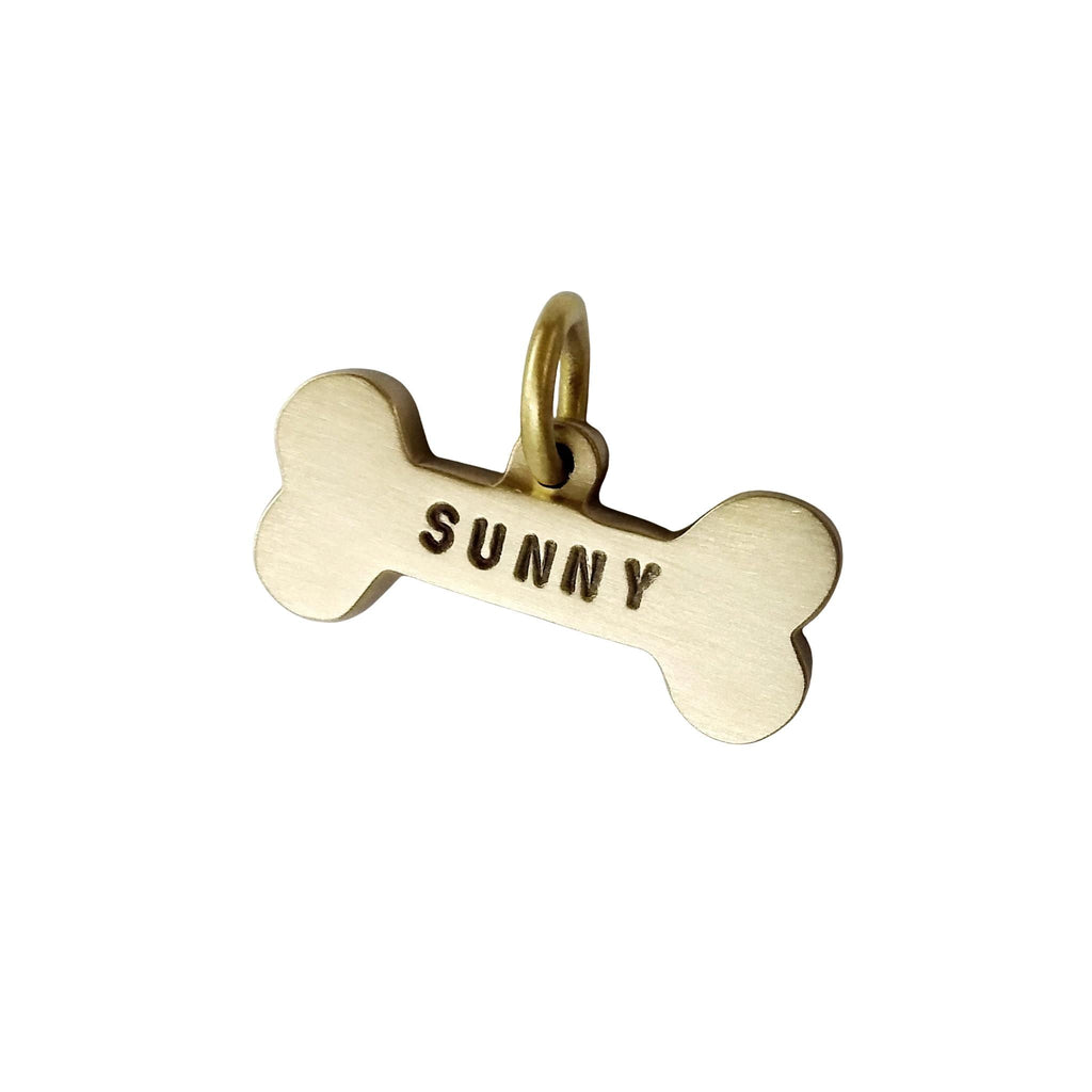 Gold bone-shaped charm with 'SUNNY' engraved on a white background