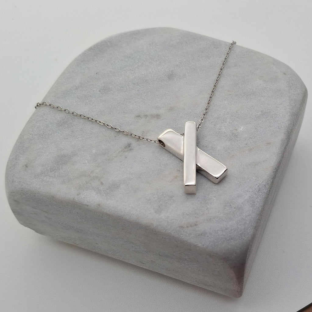 Minimalist Sterling Silver X Necklace | Dainty Kiss Cross Charm | Geometric Layering Pendant, close-up detail