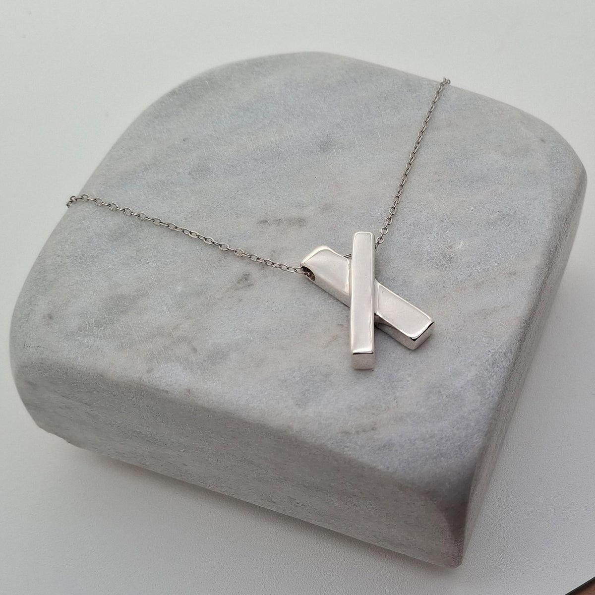 Minimalist Sterling Silver X Necklace | Dainty Kiss Cross Charm | Geometric Layering Pendant, close-up detail